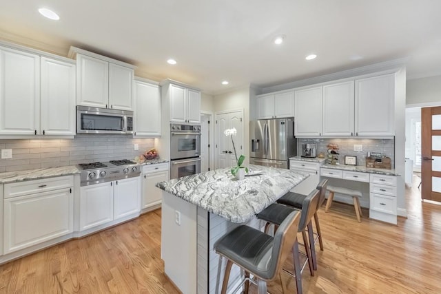 kitchen featuring a breakfast bar, light wood-style flooring, white cabinetry, and stainless steel appliances