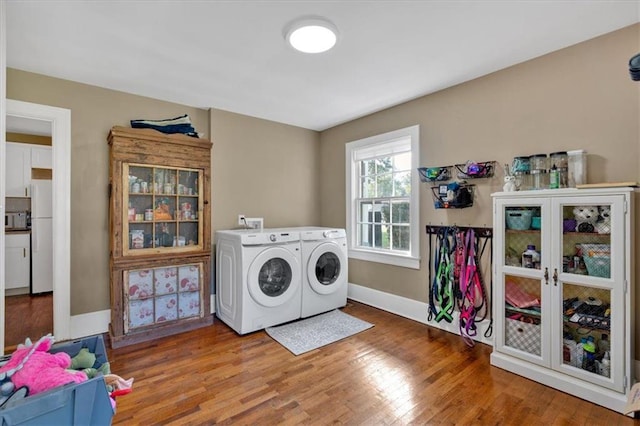 clothes washing area with hardwood / wood-style flooring and washer and dryer