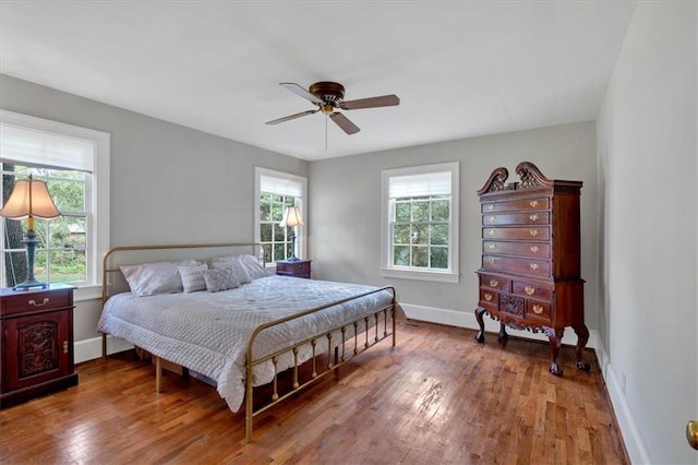 bedroom featuring multiple windows, hardwood / wood-style floors, and ceiling fan