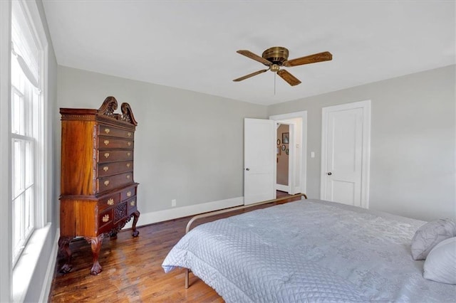 bedroom featuring multiple windows, ceiling fan, baseboards, and wood finished floors