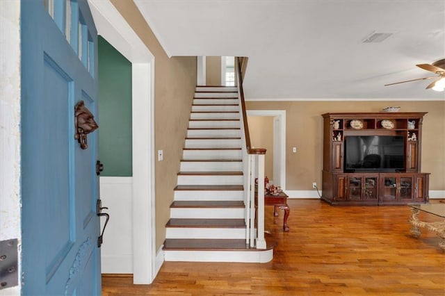 staircase featuring visible vents, wood finished floors, a ceiling fan, and baseboards