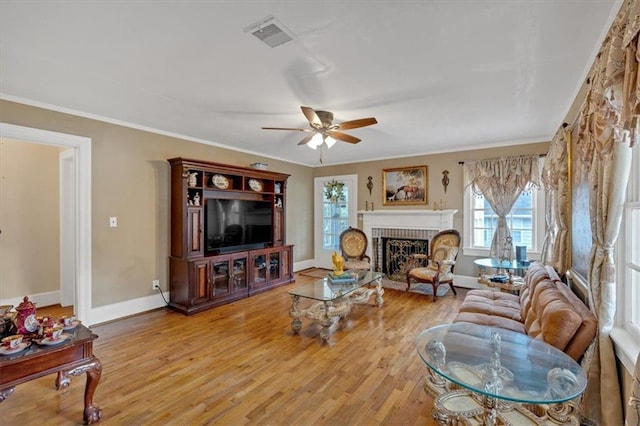 living room featuring crown molding, light wood-type flooring, and a fireplace