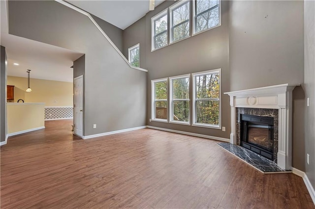 unfurnished living room featuring a premium fireplace, a high ceiling, and hardwood / wood-style flooring