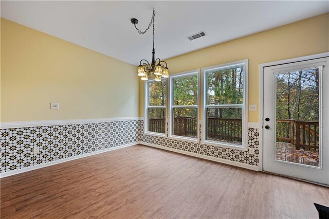 unfurnished dining area with hardwood / wood-style flooring and an inviting chandelier