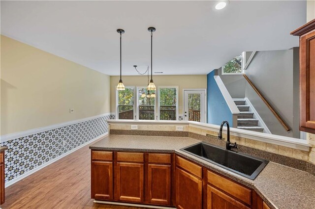 kitchen featuring light wood-type flooring, decorative light fixtures, and sink