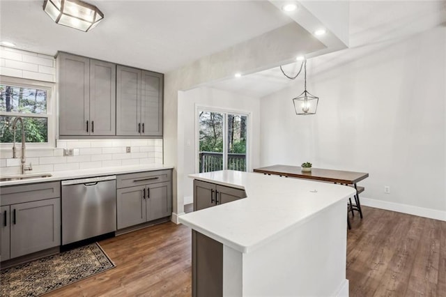 kitchen with tasteful backsplash, gray cabinetry, a center island, dishwasher, and a sink