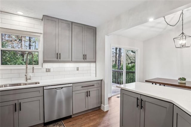 kitchen featuring a sink, gray cabinetry, light countertops, and stainless steel dishwasher