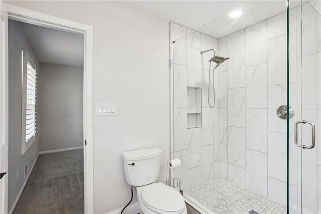 bathroom featuring a healthy amount of sunlight, a stall shower, toilet, and baseboards