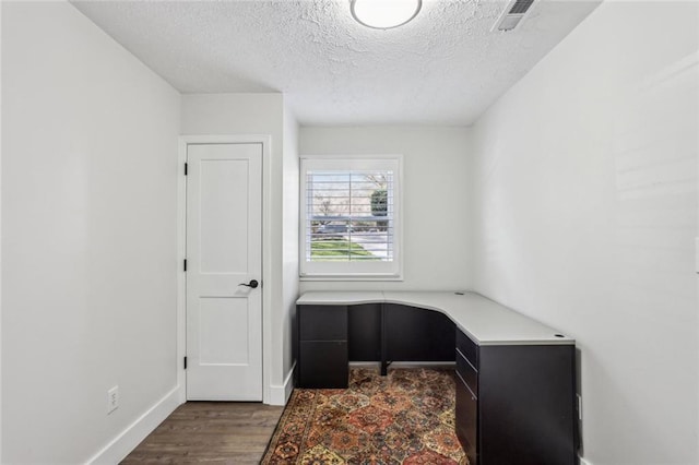 office space with visible vents, a textured ceiling, baseboards, and wood finished floors