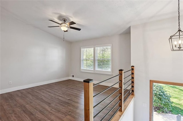 interior space with baseboards, wood finished floors, and ceiling fan with notable chandelier