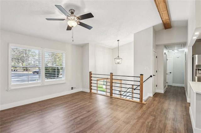 empty room with attic access, wood finished floors, baseboards, and visible vents