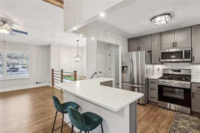 kitchen featuring visible vents, light countertops, decorative backsplash, gray cabinets, and appliances with stainless steel finishes