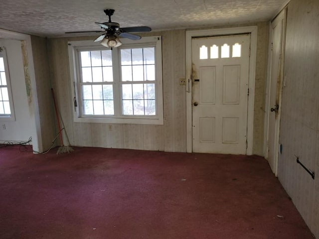 foyer entrance featuring ceiling fan, carpet flooring, and a textured ceiling