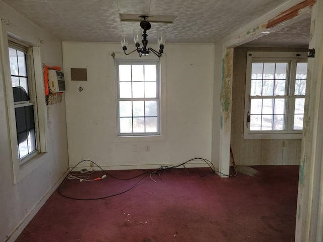 unfurnished dining area featuring a notable chandelier, a wall mounted AC, and baseboards