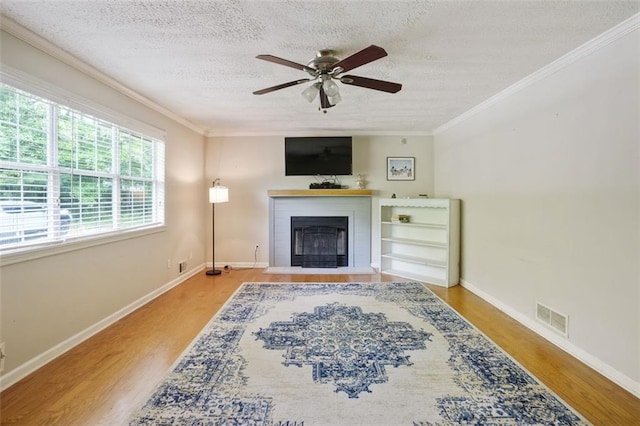 2026 Mcdaniel Mill Rd SW, Conyers, GA 30094 - living area featuring a fireplace with flush hearth, wood finished floors, a ceiling fan, crown molding, and a textured ceiling