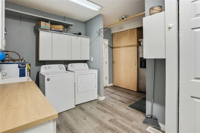 2026 Mcdaniel Mill Rd SW, Conyers, GA 30094 - laundry area featuring washer and clothes dryer, light wood-style flooring, cabinet space, and gas water heater