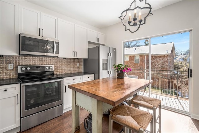 kitchen with appliances with stainless steel finishes, an inviting chandelier, white cabinets, and backsplash