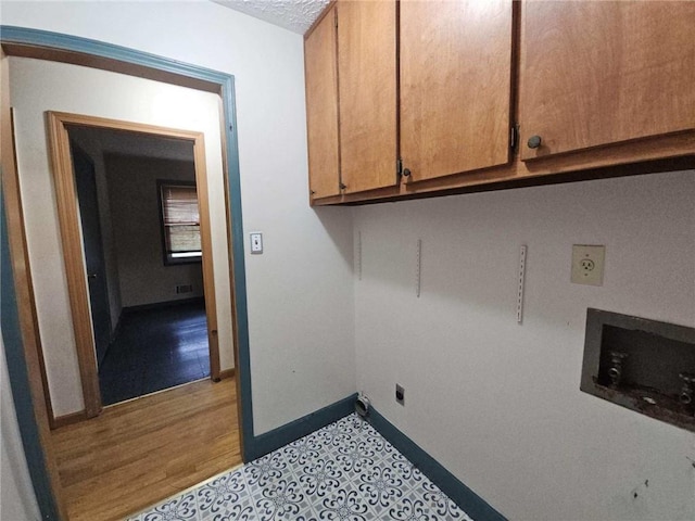 clothes washing area with cabinet space, hookup for a washing machine, a textured ceiling, electric dryer hookup, and baseboards