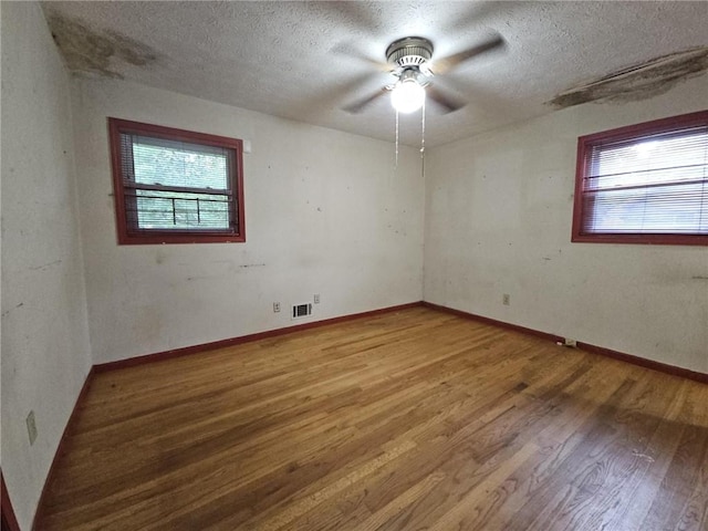 unfurnished room featuring ceiling fan, light wood-type flooring, a textured ceiling, and visible vents
