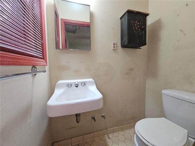bathroom with baseboards, a sink, tile patterned floors, and toilet