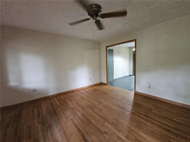 unfurnished room with a textured ceiling, ceiling fan, baseboards, and wood finished floors
