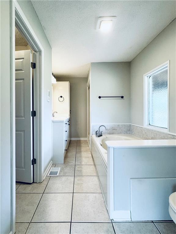 238 Marks Rd, Mansfield, GA 30055 - full bathroom featuring vanity, tile patterned floors, a garden tub, and a textured ceiling