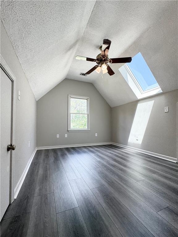 238 Marks Rd, Mansfield, GA 30055 - additional living space with a textured ceiling, dark wood-type flooring, a skylight, ceiling fan, and lofted ceiling