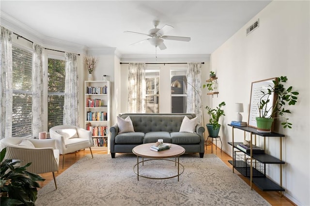 living area featuring visible vents, wood finished floors, ceiling fan, and crown molding