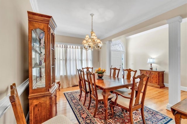 dining space with crown molding, light wood-style floors, and ornate columns