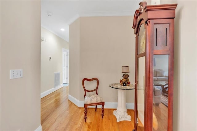 living area featuring visible vents, crown molding, light wood-type flooring, and baseboards