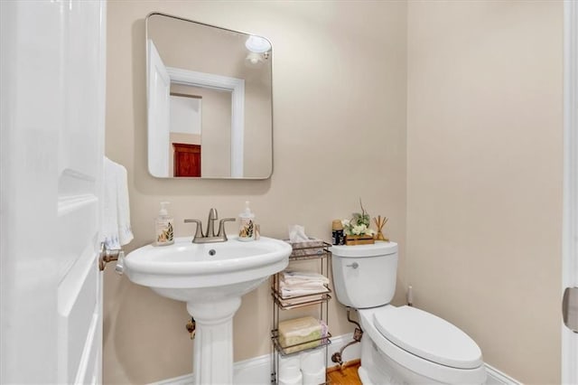 half bath featuring toilet and baseboards