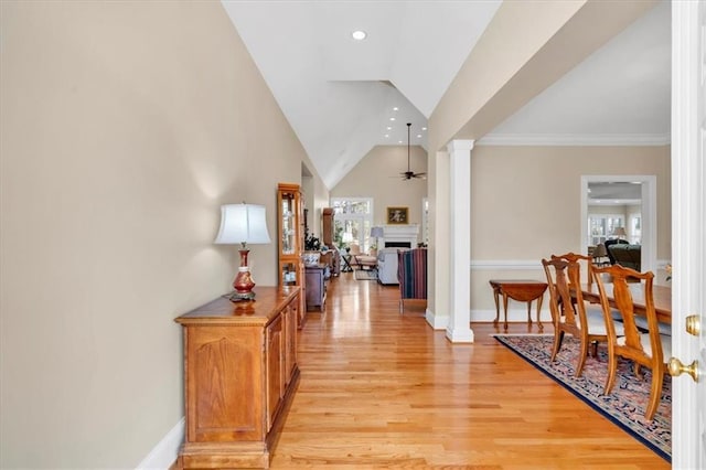 interior space featuring baseboards, light wood-type flooring, decorative columns, recessed lighting, and high vaulted ceiling