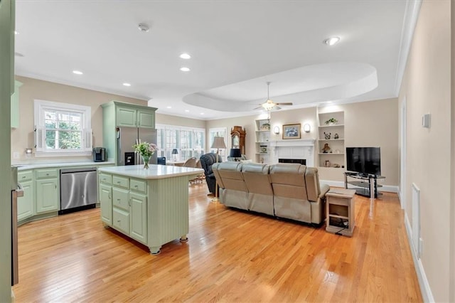 kitchen featuring light countertops, a tray ceiling, appliances with stainless steel finishes, a fireplace, and green cabinetry