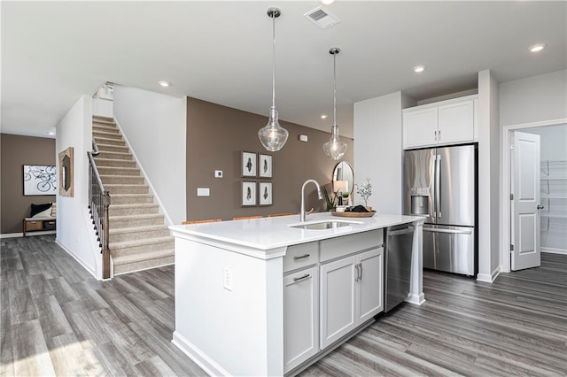 kitchen with stainless steel appliances, a sink, wood finished floors, light countertops, and recessed lighting