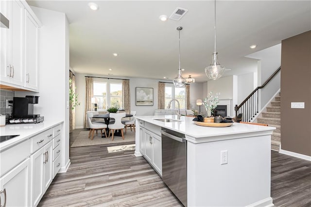 kitchen with a sink, dishwasher, light wood finished floors, light countertops, and baseboards