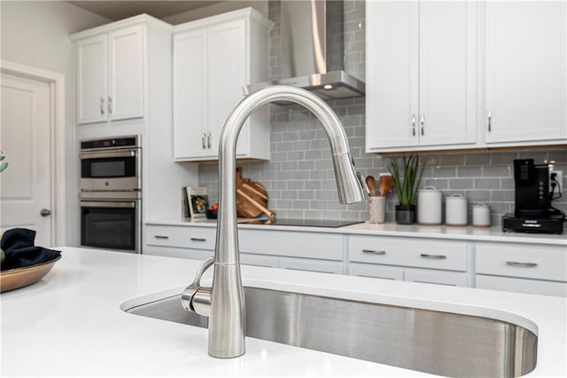 kitchen featuring double oven, tasteful backsplash, white cabinetry, and light countertops