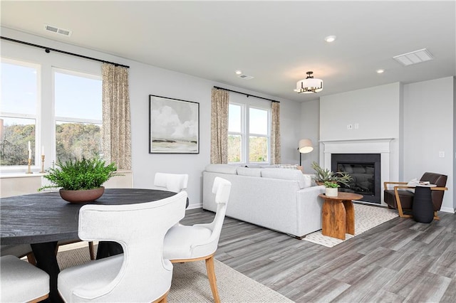 living area featuring light wood-type flooring, recessed lighting, baseboards, and a glass covered fireplace