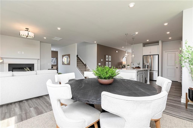 dining space with wood finished floors, stairs, recessed lighting, and a fireplace