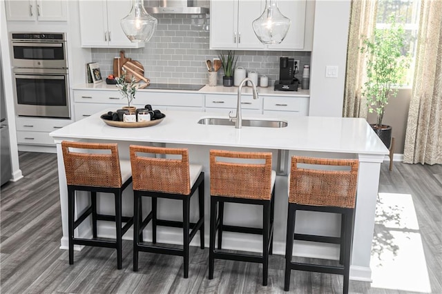 kitchen featuring a sink, wood finished floors, stainless steel double oven, and black electric stovetop
