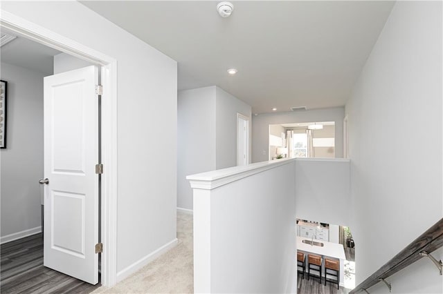 hall with an upstairs landing, baseboards, and recessed lighting