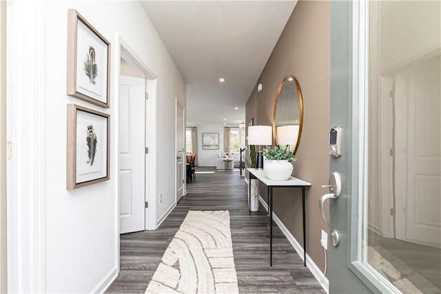 hall featuring dark wood-type flooring, recessed lighting, and baseboards