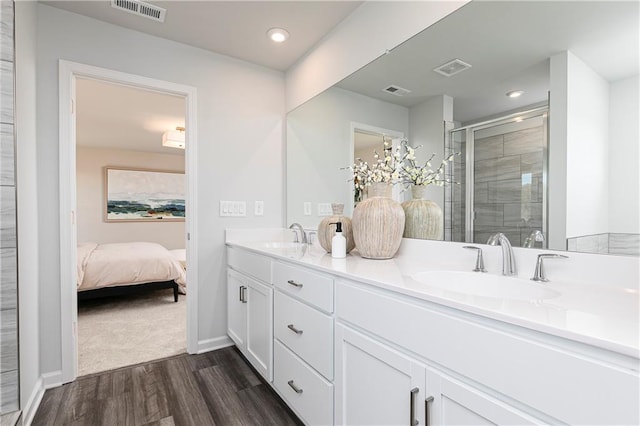 ensuite bathroom with wood finished floors, a shower stall, double vanity, recessed lighting, and baseboards