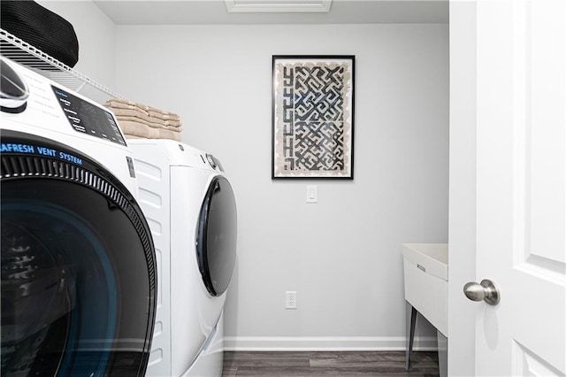clothes washing area with washer and clothes dryer, wood finished floors, and baseboards