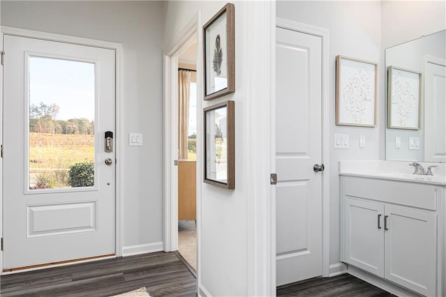 foyer entrance with dark wood-style flooring and baseboards