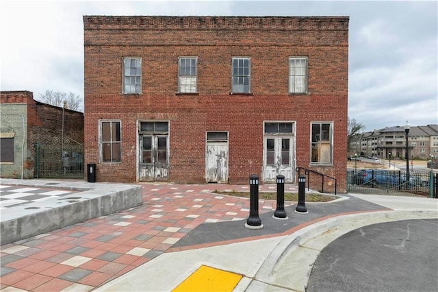 view of front facade featuring brick siding, french doors, and fence