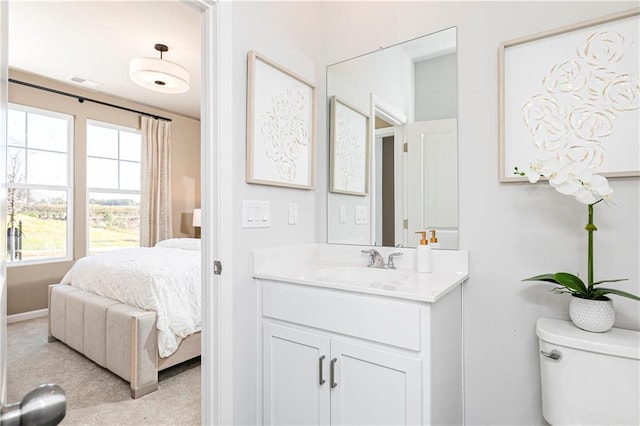 bathroom with connected bathroom, vanity, toilet, and baseboards