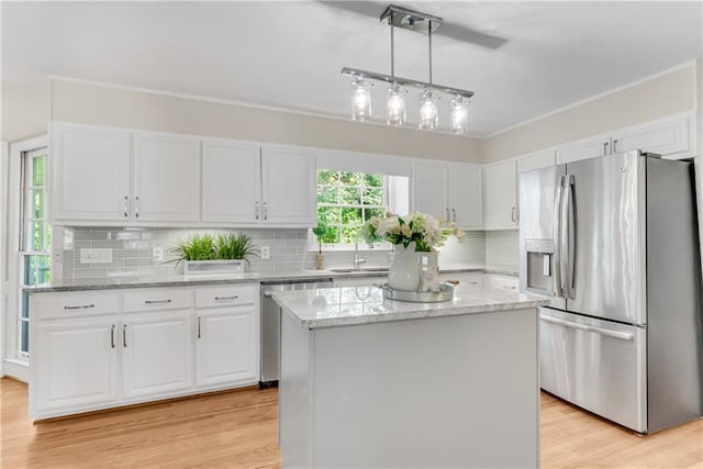 kitchen featuring appliances with stainless steel finishes, sink, white cabinetry, a kitchen island, and hanging light fixtures