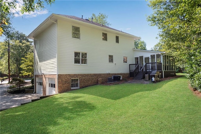 rear view of property with a yard, a garage, and a sunroom