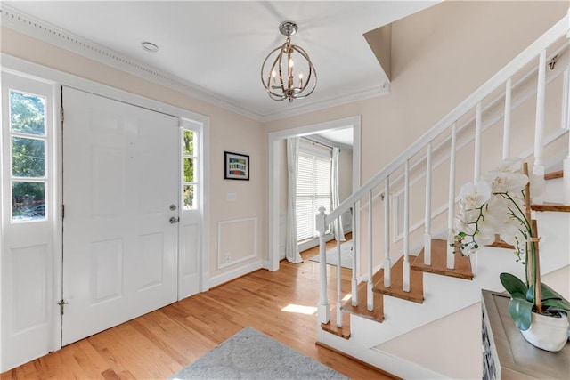 entrance foyer featuring light hardwood / wood-style floors, crown molding, and an inviting chandelier