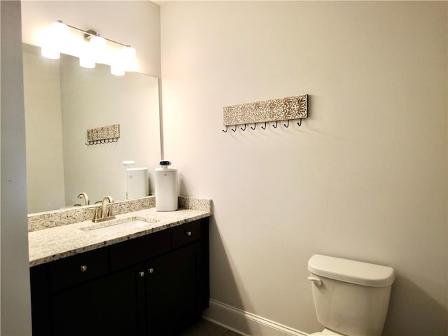 bathroom featuring vanity, baseboards, and toilet